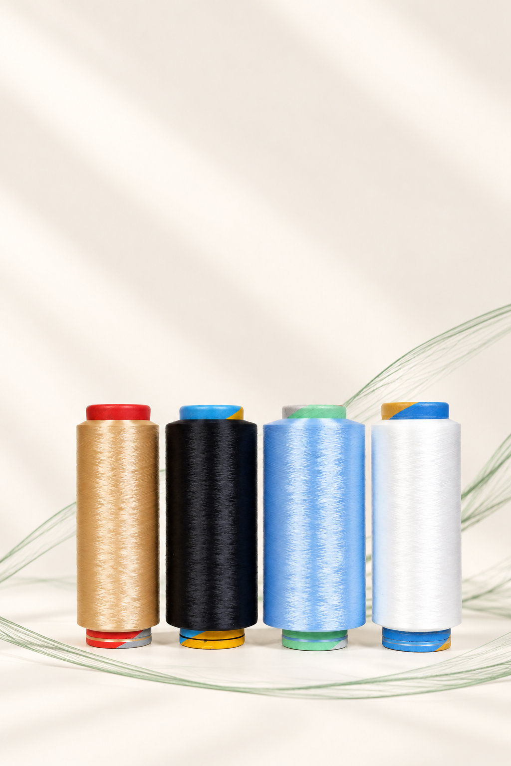 Four spools of nylon yarn in gold, black, blue and white, with a green filament motif